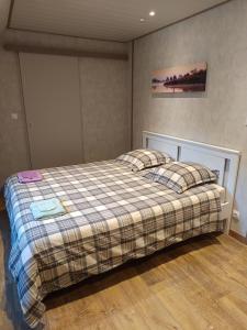 Un dormitorio con una cama con una manta a cuadros. en LA CLIMONTAINE BIS, en Urbeis