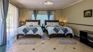 a bedroom with two beds and a window at Zambezi Family Lodge - Elephant Room in Victoria Falls