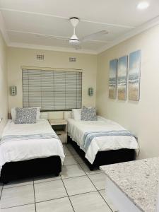a bedroom with two beds and a window in it at Banana Beach Club Unit A2 in Port Shepstone +12 photos