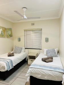 a bedroom with two beds and a window at Banana Beach Club Unit A2 in Port Shepstone