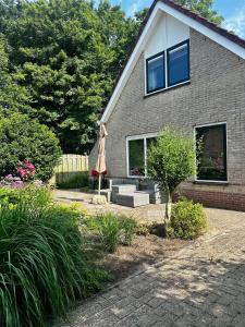 ein Haus mit einer Terrasse mit Sonnenschirm in der Unterkunft - Tulipa - Vakantiehuis nabij de bloembollenvelden, het meer en strand in Noordwijkerhout