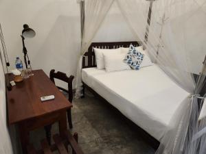 a small bedroom with a bed and a table at Zee Golf Affordable Luxury in Galle