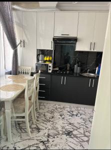 Una cocina con mesa y sillas y una cocina con gabinetes blancos. en Vokzal House, en Samarkand