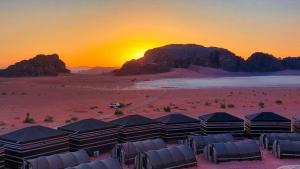 a group of tents in the desert with the sunset at Wadi Rum Majestic Camp in Wadi Rum