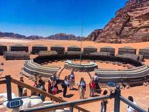 a group of people standing around a circular building in the desert at Wadi Rum Majestic Camp in Wadi Rum