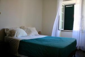 ein Schlafzimmer mit einem Bett mit einer grünen Decke und einem Fenster in der Unterkunft Mountain View Villa in São Vicente