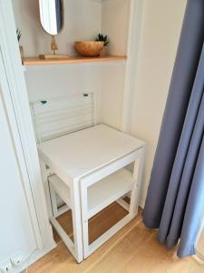 a small white table in a room with a blue curtain at Cosy 2 pièces proche de Paris avec parking in Gentilly