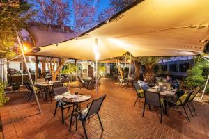 an outdoor patio with tables and chairs and umbrellas at Auas City Hotel in Windhoek