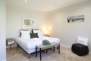a bedroom with a large white bed and a table at Résidence Les Suites Du Ferret in Cap-Ferret