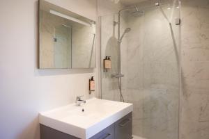 a bathroom with a sink and a glass shower at Résidence Les Suites Du Ferret in Cap-Ferret