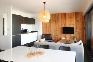 a kitchen and dining room with a white table and chairs at Résidence Les Suites Du Ferret in Cap-Ferret