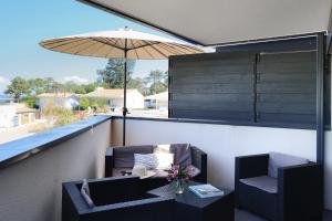 a balcony with two chairs and a table and an umbrella at Résidence Les Suites Du Ferret in Cap-Ferret