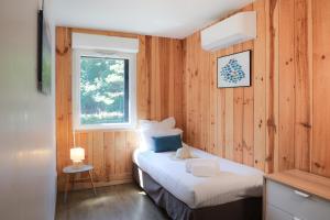 a bedroom with two beds with wooden walls and a window at Résidence Les Suites Du Ferret in Cap-Ferret