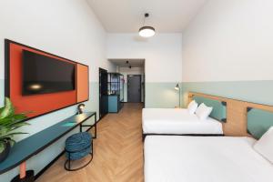 ein Hotelzimmer mit zwei Betten und einem Flachbildfernseher in der Unterkunft CX Milan Bicocca in Mailand