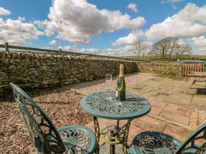 a table with a bottle of wine and two glasses at School House Cottage in Buxton