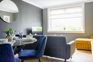 a dining room with a table and blue chairs at Andrew House in Bathgate