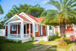 a red house with a palm tree in front of it at Mamalla Kudil Resort in Mahabalipuram