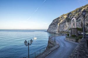 a road next to the ocean with a cliff at Il Nido di Nenna Apartment in Meta