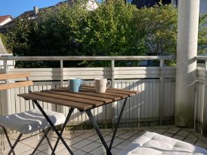 a wooden table with two mugs on a balcony at Studio-Priv.Parkplatz-Balkon-Wlan-Netflix-SmartTV in Deizisau