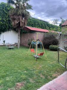 un parque infantil en un patio con una palmera en La Maison de Marinés, en Villa Nueva
