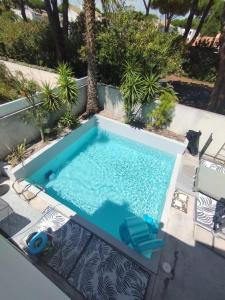una piscina in un cortile con due sedie a sdraio blu e un parasole per piscina di Villa Golf LGM a La Grande-Motte