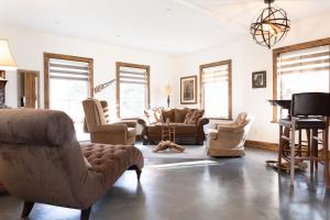 a living room with couches and chairs and a piano at La Ruelle Hébergement in Saint-Siméon