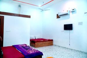 a room with a bed and a tv on a wall at Mohit Guest IN in Vrindāvan +14 photos