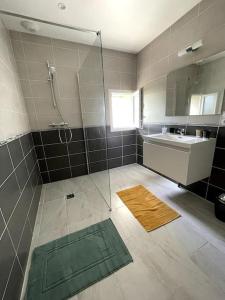 un bagno con doccia, lavandino e specchio di Le logis des Lilas a Corme-Royal