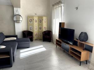 un soggiorno con divano e TV a schermo piatto di Le logis des Lilas a Corme-Royal