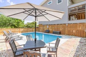 a table with an umbrella next to a pool at Salty Beach in Duck