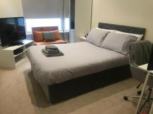 ein Schlafzimmer mit einem Bett, einem Fernseher und einem Stuhl in der Unterkunft Queen Street Quayside Apartment, NE1 Grade 2 Listed in Newcastle upon Tyne