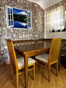 a wooden table with two chairs and a stone wall at Holiday Home Nikolić in Njeguši +22 photos