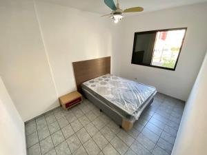 a small bedroom with a bed and a television at Pé na Areia Canto do Forte III in Praia Grande