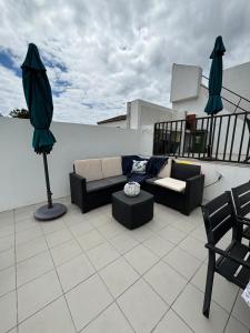 a patio with a couch and an umbrella on a roof at Casa da Lara in Lagoa
