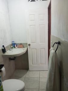 a bathroom with a toilet and a sink and a door at Guadalupe Herrera in Tola