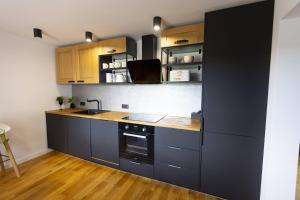 a kitchen with black cabinets and wooden floors at Ten Dom in Malbork