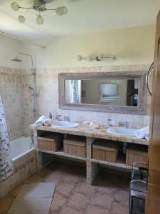 a bathroom with two sinks and a tub and a mirror at Villa provençale à Arles avec piscine privée et vue jardin. in Arles