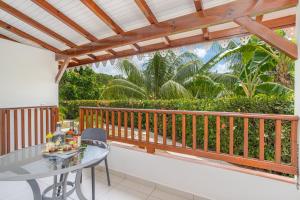 d'un balcon avec une table et une pergola en bois. dans l'établissement Ixora au Refuge de Madiana à Schoelcher, à Schœlcher