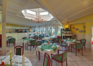 a restaurant with tables and chairs and a chandelier at Landhotel Schwarzer Adler in Sülzetal