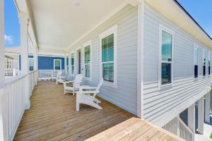 a porch with white chairs and windows on a house at Salt & Stone Villas in Galveston