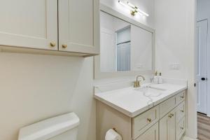 a white bathroom with a sink and a mirror at Salt & Stone Villas in Galveston +23 photos