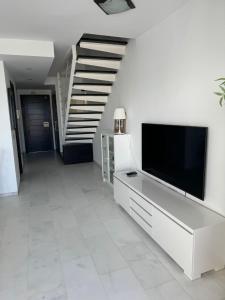 a living room with a television and a staircase at REf 107 DUPLEX DUNA PLAYA ZAHARA in Zahara de los Atunes