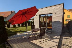 施伦贝格TinyHouse - (D)ein Ferienhaus的甲板上配有红色遮阳伞和桌椅