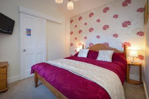 a bedroom with a large bed with purple sheets at Craig Y Glyn in Pwllheli