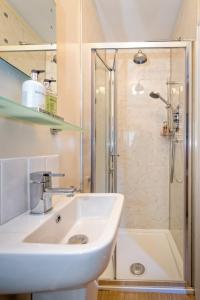 La salle de bains blanche est pourvue d'un lavabo et d'une douche. dans l'établissement Craig Y Glyn, à Pwllheli