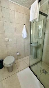 a bathroom with a toilet and a glass shower at Hotel Tubarao in Tubarão