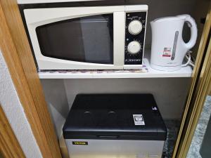 a microwave sitting on a shelf next to a printer at Habitación Familiar in Madrid