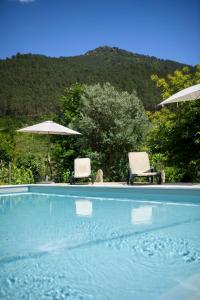 two chairs and umbrellas next to a swimming pool at Afonso's House Gerês I in Braga