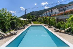a swimming pool with chairs and a house at Afonso's House Gerês I in Braga