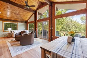 a living room with a ceiling fan and large windows at Belleau Lake Escape in Wakefield